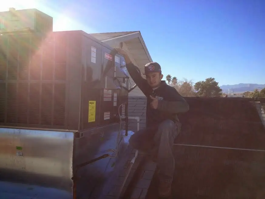 HVAC technician performing Heat Pump Repair on a rooftop unit in Kaysville
